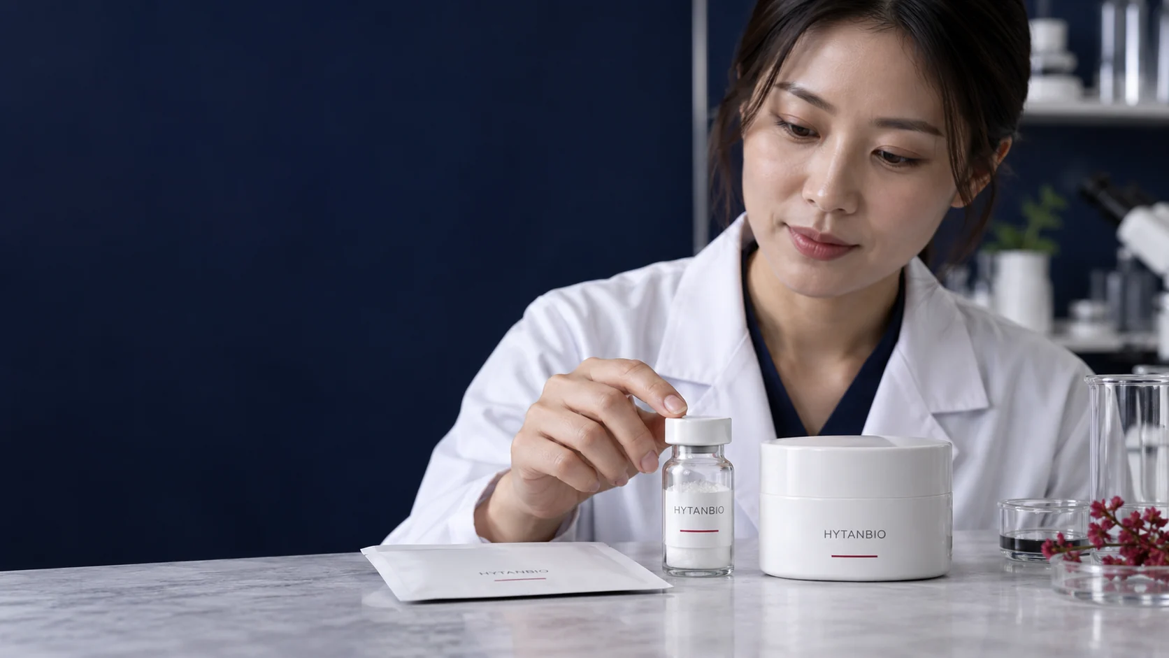 A small ingredient vial stands beside a white cosmetic jar and a closed sample envelope — illustrative development scene