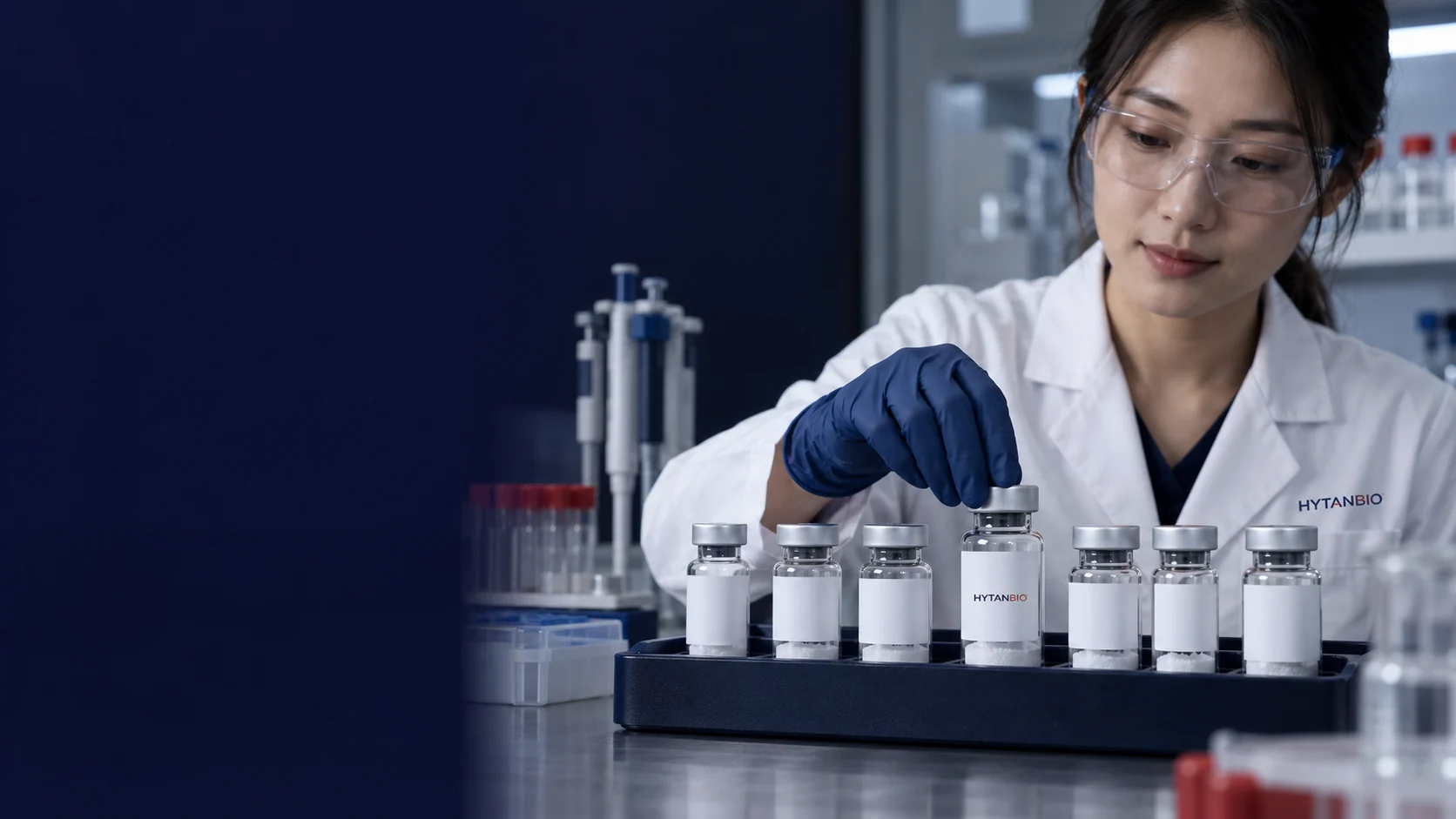 A row of upright clear capped vials with different neutral label widths in a fitted protective tray — illustrative development scene