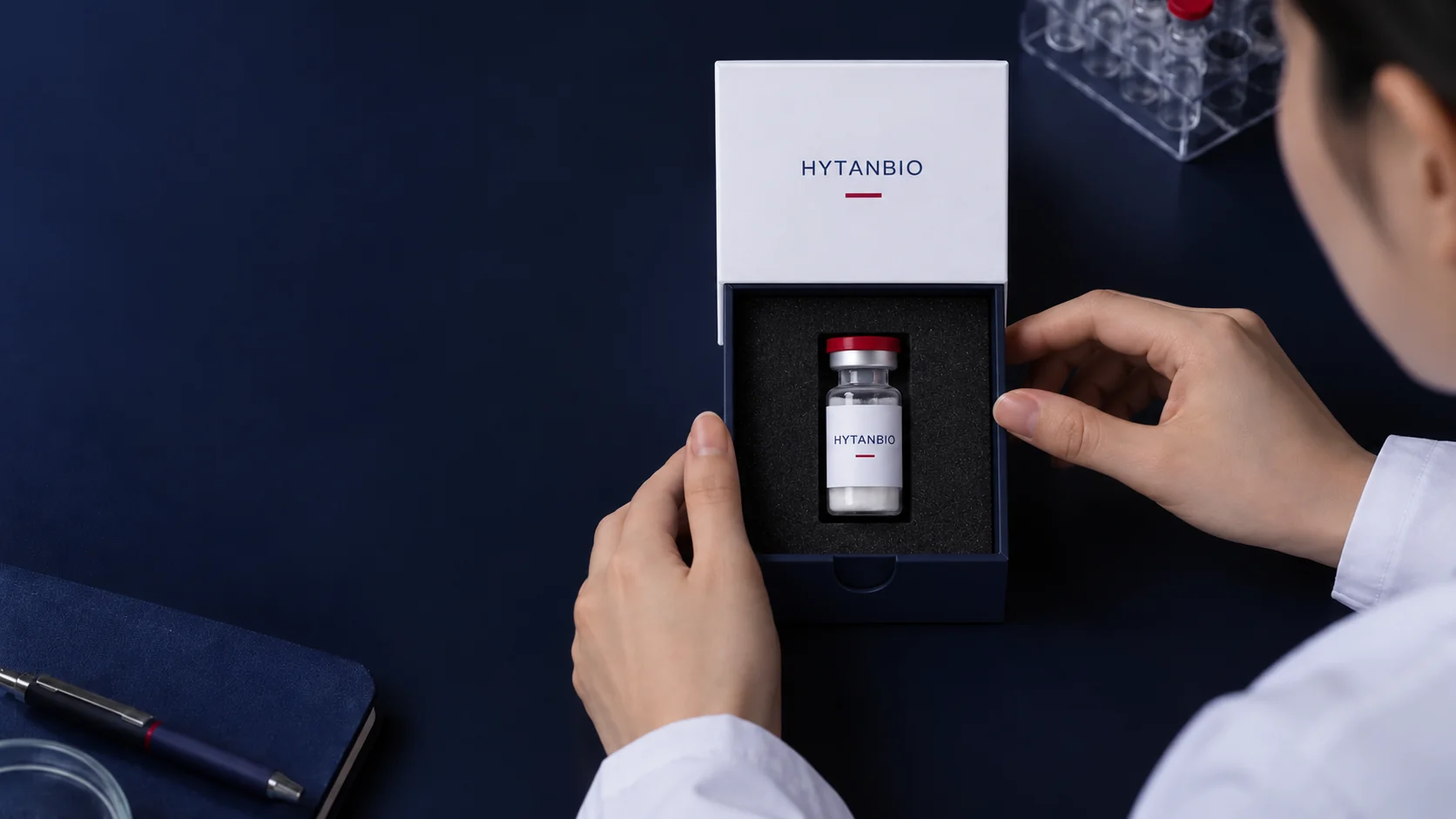 One upright peptide sample vial in a protective foam insert beside a plain white shipping sleeve — illustrative development scene