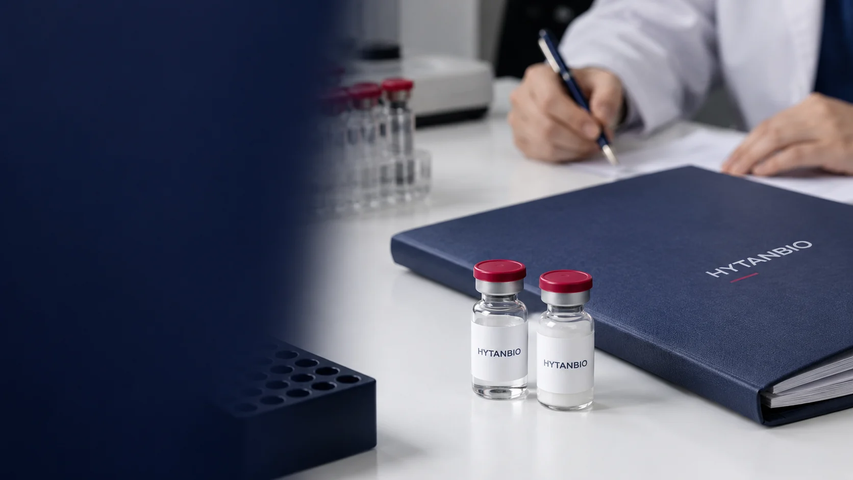 Two upright labelled reference vials and a closed specification folder on a matte white surface — illustrative development scene